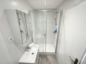 a white bathroom with a shower and a sink at Cosy appt Part Dieu Félix 3 in Lyon