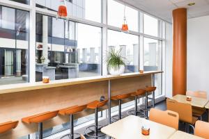 a restaurant with tables and chairs and large windows at ibis Budget Luxembourg Sud in Livange