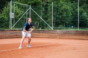 un hombre sosteniendo una raqueta de tenis en una pista de tenis en Gastwirtschaft Hold, en Mönichwald