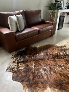 a brown leather couch in a living room with a rug at Market on 5 in Piet Retief