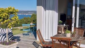 a patio with a table and chairs and a view of the ocean at Knysna Private Estate Lagoon Apartment - Garden Apartment - Secure Estate in Knysna