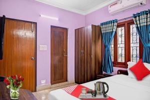 um quarto com paredes roxas, uma cama e uma mesa em Flagship Himgiri Guest House em Calcutá