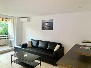 a living room with a black couch and a table at Grand studio Standing avec terrasse et parking in Sainte-Maxime