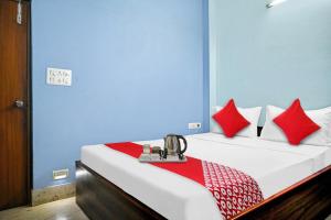 um quarto com uma cama com almofadas vermelhas e brancas em Flagship Himgiri Guest House em Calcutá