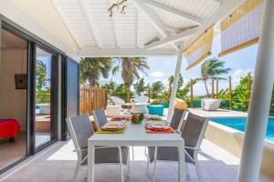 una mesa blanca y sillas en un patio con piscina en Iguane House Villas & Micro Spa, en Sainte-Anne