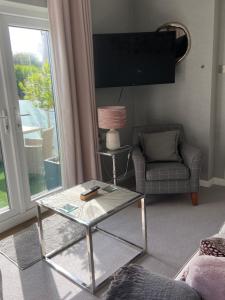 a living room with a glass coffee table and a television at Dewcroft in Horsley