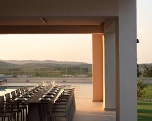 a long row of tables and chairs on a patio at Casa Beleza Villa, a Mythical Retreat, By ThinkVilla in Perama