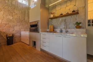 a kitchen with white cabinets and a stone wall at Chalé Alto da Bela Vista por Carpediem in Guaramiranga +44 photos