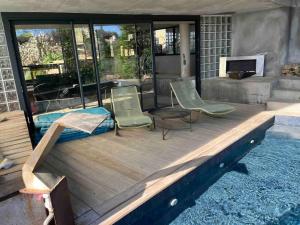 una terrazza in legno con 2 sedie e una piscina di Loft sur le Mont Saint Clair - Sète a Sète