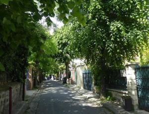 une rue bordée d'arbres avec une clôture et des arbres dans l'établissement Le Cocon du Pré-Saint-Gervais, à Le Pré-Saint-Gervais