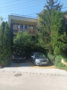 2 voitures garées sur un parking en face d'un immeuble dans l'établissement Tavaszház Apartmanok, à Balatonfüred
