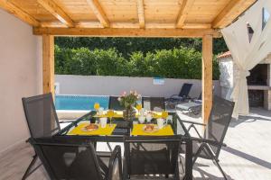 un tavolo e sedie su un patio con piscina di LIFE - NEW and LUXURY holiday house a Kaštela (Castelli)