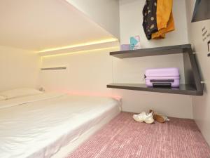 a bedroom with a bed and a pink suitcase on a shelf at CityHub Amsterdam in Amsterdam