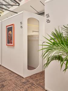une chambre blanche avec un tableau et une plante dans l'établissement CityHub Amsterdam, à Amsterdam
