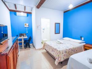 1 dormitorio con paredes azules, 1 cama y escritorio en VELINN Pousada Face Norte, en Ilhabela