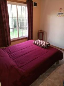 Una gran cama púrpura con una almohada encima. en Casa Doña Nelly - Sierras, naturaleza, y descanso en Villa Yacanto