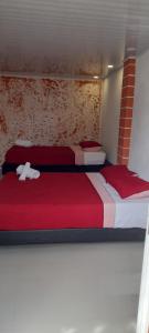 two beds in a room with red and white sheets at POSADA HIGH TIDE in San Andrés