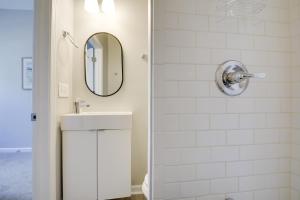 a white bathroom with a sink and a mirror at Indianapolis Home with Porch - Close to Mile Square! in Indianapolis