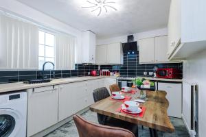 a kitchen with a wooden table with chairs and a washing machine at Home Away Apartment in Manchester