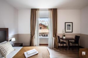 ローマにあるホテル ブティック ナツィオナーレのベッド、テーブル、窓が備わる客室です。