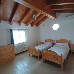 1 Schlafzimmer mit 2 Betten, einem Fenster und Holzdecken in der Unterkunft Agriturismo Trabucco in Casale sul Sile