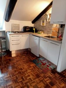 una cucina con armadietti bianchi e pavimenti in legno di La Mole apartment a Torino