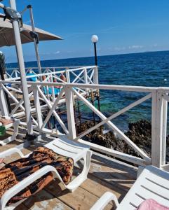 una terraza con sillas y sombrilla y el océano en Casaafauka, en Carini