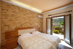 a bedroom with a bed and a brick wall at Castello Rosso Hotel in Nea Stira