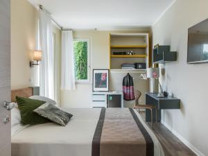 a bedroom with a bed and a desk and a window at Hotel Ca' Mura in Bardolino