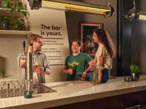a group of three people standing behind a counter with wine glasses at CityHub Amsterdam in Amsterdam +33 photos
