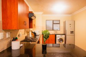 a kitchen with wooden cabinets and a washer and dryer at Premium Getaway @ la Bella Costa in Pretoria