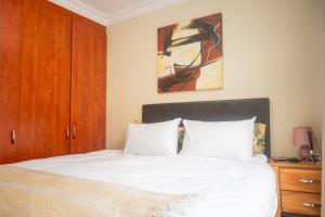 a bedroom with a bed with white sheets and a painting at Premium Getaway @ la Bella Costa in Pretoria