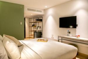 a bedroom with a white bed with a tv on the wall at Hotel Shoshana - Adults Only in Eilat