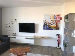 sala de estar con TV en una pared blanca en Casa das Falcoeiras - AL com vista Ria en Aveiro
