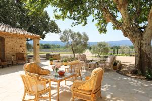 um pátio com uma mesa e cadeiras debaixo de uma árvore em Domaine Egenia em Roussillon