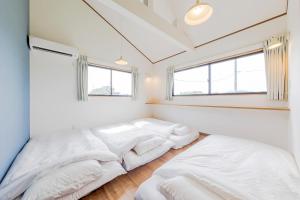 two beds in a bedroom with white walls and windows at 三浦海岸 SealightVilla A棟 in Miura
