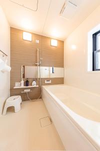 a white bathroom with a tub and a toilet at 三浦海岸 SealightVilla A棟 in Kōembō