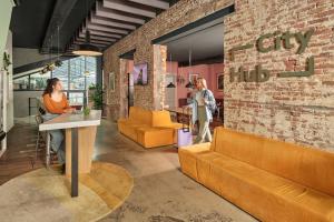 a woman sitting at a table in a lobby at CityHub Amsterdam in Amsterdam