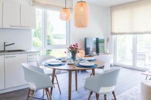 a kitchen and dining room with a wooden table and white chairs at Weiße Villen "das Meeresloft" in Boltenhagen