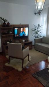 a living room with a couch and a tv at Aconchegante apt c/ garagem in Serra Negra