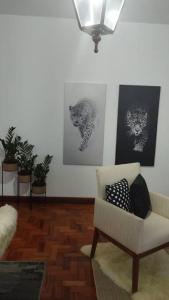 a living room with a chair and pictures on the wall at Aconchegante apt c/ garagem in Serra Negra