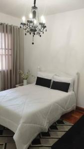 a bedroom with a large white bed with a chandelier at Aconchegante apt c/ garagem in Serra Negra