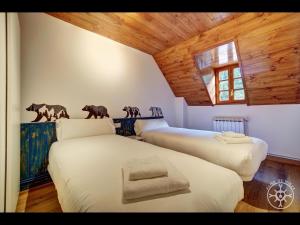 two beds in a room with wooden ceilings at CASA DEL VALLE de Alma de Nieve in Tredós