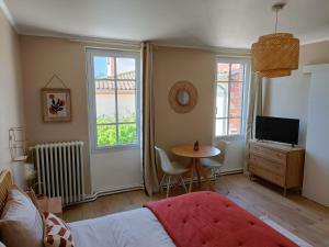 a bedroom with a bed and a table and a tv at Chez Lucy&Nico in Verfeil