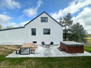 a white building with a picnic table and a barbecue at Urriðafoss Waterfall Villa in Selfoss