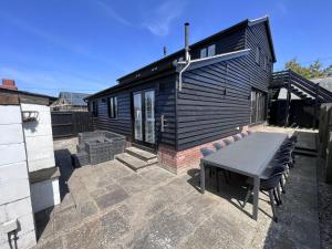 a patio with a table and chairs in front of a house at The Cart Lodge at Lee Wick Farm Cottages & Glamping in Saint Osyth