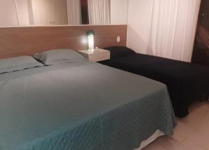 a bedroom with two beds and a table with a lamp at Apartamento na Praia do Saco - Condomínio Villa das Águas in Estância