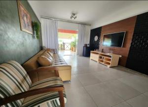 a living room with a couch and a television at Apartamento na Praia do Saco - Condomínio Villa das Águas in Estância