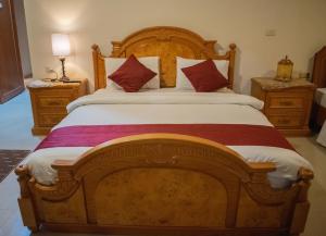 Un dormitorio con una gran cama de madera con almohadas rojas en Twilight Hotel Petra, en Wadi Musa