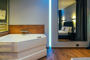 uma casa de banho com uma banheira e um quarto com uma cama em Pines Hotel em Atenas